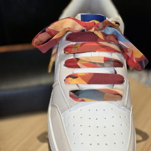 Orange handmade fabric shoelaces with artistic pattern styled on casual sneakers.